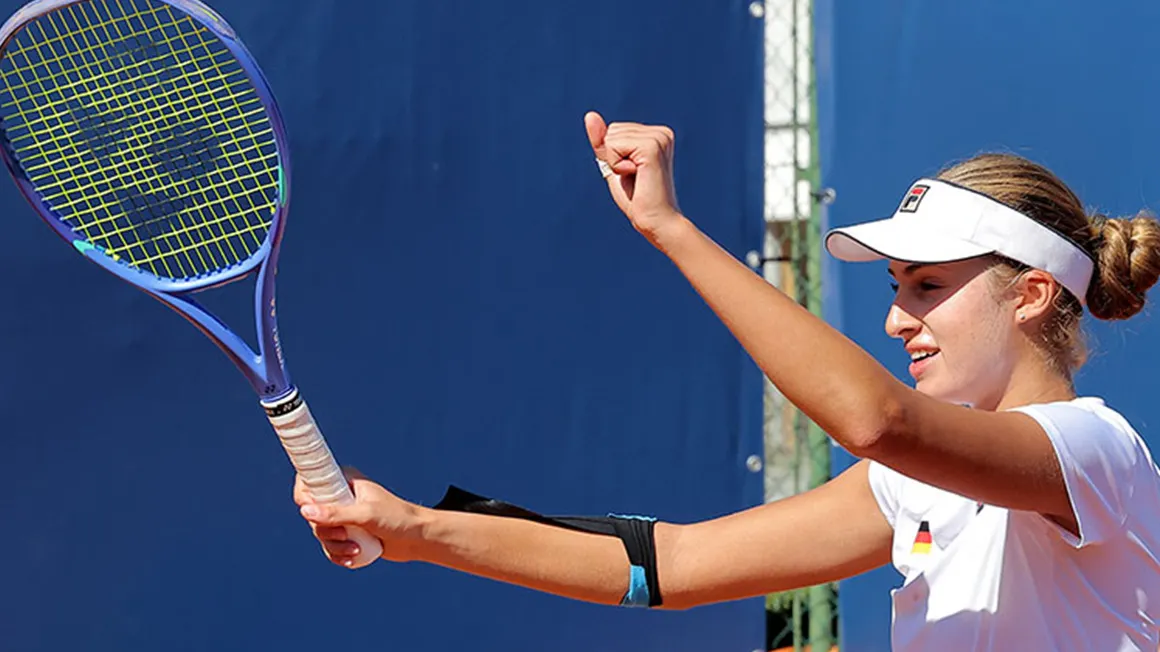 Tennis player Milena Steinkamp celebrates on a clay court with a raised fist and racket in hand.